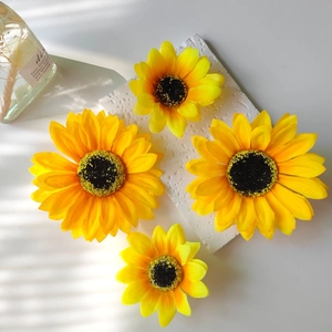 Detailed macro view of four artificial sunflower heads in two sizes on stone base