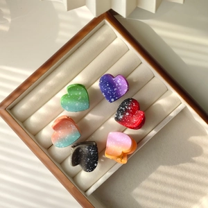 Detail view of heart-shaped mini hair claws with gradient polka dot pattern in a display box