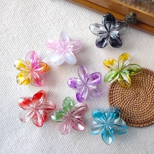 Close-up of eight colorful plumeria flower hair claws in a decorative wooden box