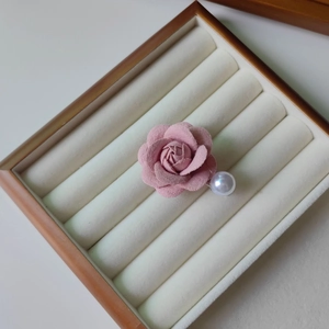 Détail de la pince à cheveux camélia rose avec perle dans un écrin à bijoux en velours