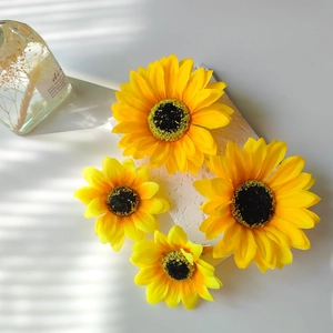 Set of four vibrant yellow sunflower hair clips on a textured stone surface with shadows