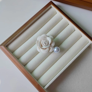 Détail d'une pince à cheveux camélia en tissu blanc avec perle sur bois