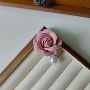 Détail de la barrette camélia en tissu rose ornée d'une grande perle blanche