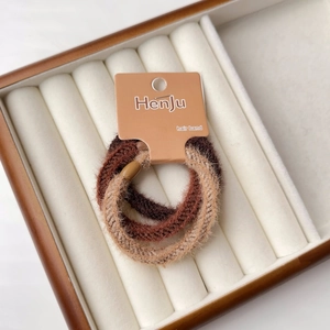 Vista macro dettagliata di un set di 3 elastici per capelli in peluche nei toni marroni