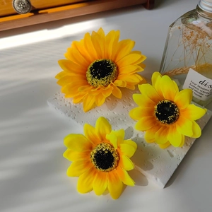 Detailed view of three artificial sunflower hair clips on a stone surface with artistic shadows