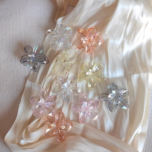 Detailed view of iridescent flower hair claws in multiple colors on beige satin fabric
