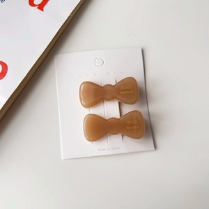 Vue détaillée de barrettes à cheveux nœuds en acétate ambré sur carte de présentation