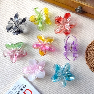 Detailed overhead view of 8 colorful plumeria flower claw clips in various gradient finishes