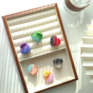 Detail view of colorful gradient heart hair claws with white polka dots on velvet tray