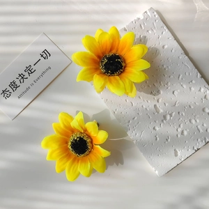 Detailed close-up of a pair of lifelike sunflower hair clips with high-quality fabric texture