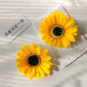 Detailed top view of artificial sunflower hair clips with textured fabric on white stone
