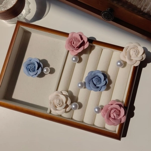 Détail de barrettes camélia en tissu avec perles en rose, bleu et blanc crème