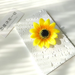 Macro detail of artificial sunflower hair clip with vibrant petals on textured stone