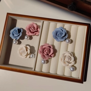 Détail de barrettes camélia en velours avec perles dans une boîte à bijoux en bois