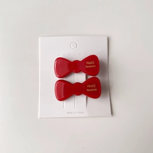 Détail de barrettes nœuds en acétate rouge avec inscription dorée faite à la main