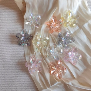 Close-up of translucent gradient plumeria flower hair claws on a white satin fabric