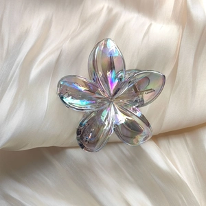 Detail of transparent gradient frangipani hair claw clip on soft cream satin fabric