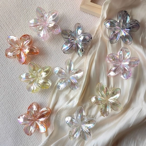 Close-up of translucent AB color flower hair claws with iridescent finish and metal springs