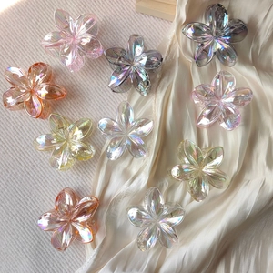 Flat lay of gradient frangipani flower hair claws in iridescent acrylic colors