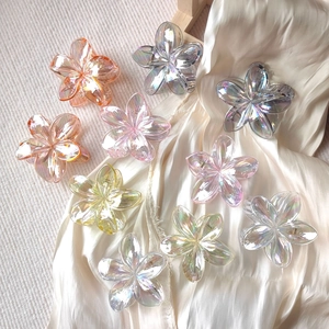 Macro shot of colorful iridescent resin flower hair claws on soft silk fabric