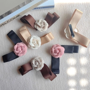 Détail de la pince à cheveux élégante avec nœud en satin, fleur de camélia et bec de canard