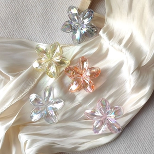 Detailed close-up of colorful iridescent plumeria flower hair claws on white silk