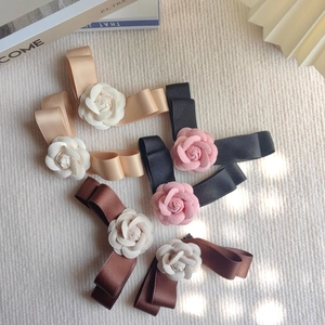 Détail de barrettes à cheveux camélia en ruban champagne, noir et marron avec nœud élégant