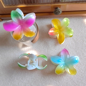 Close-up of four gradient tropical frangipani flower hair claws with glitter detail