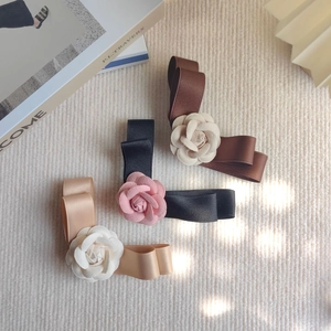 Détails des barrettes à nœuds et camélias en noir, marron et couleur champagne élégant