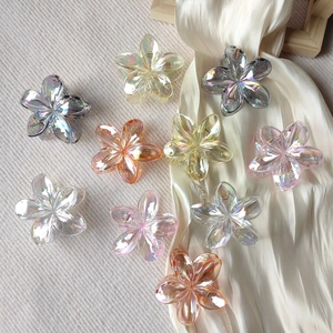 Macro detail of acrylic plumeria flower hair clips with rainbow iridescent coating