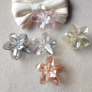 Detail of five-piece gradient flower hair claws with iridescent finish on fabric
