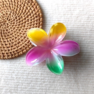 Close-up of colorful gradient resin flower hair claws on a textured knit background