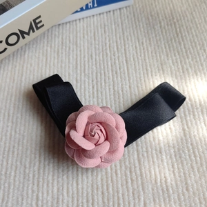 Vue détaillée de la pince à cheveux camélia en velours rose avec ruban satiné noir