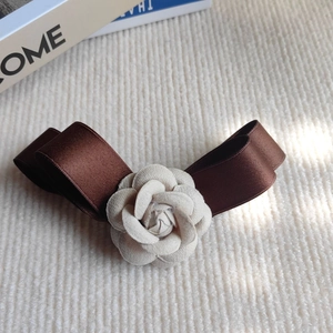 Vue détaillée de l'élégante fleur de camélia et du nœud en ruban café sur tissu tricoté