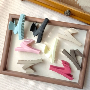 Close-up of matte Z-shape hair claw clips in 8 Morandi colors on a textured tray