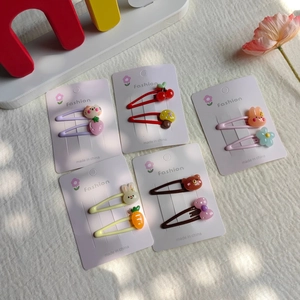 Flat lay of five pairs of cartoon resin hair clips for girls on a white fabric background