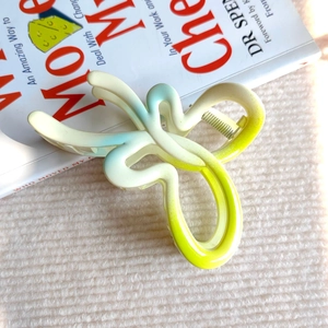 Dettaglio di una molletta per capelli a farfalla sfumata con finitura opaca e molla