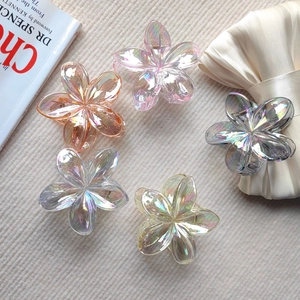 Set of five iridescent flower hair claws in multiple colors on a soft corduroy background