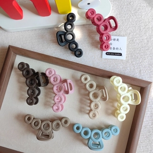 Flat lay of minimalist hollow circle shark hair claws in eight assorted matte colors