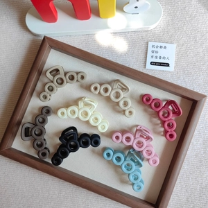 Detail view of eight colorful hollow circle hair claws on a rustic wooden tray display