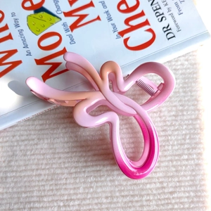 Dettaglio della molletta per capelli a farfalla sfumata rosa con finitura opaca