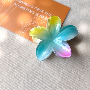Macro detail of Frangipani hair claw clip showing pearlescent yellow-blue-pink gradient finish