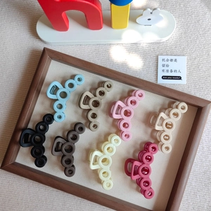 Close-up of 8 matte claw clips in pastel colors with circular cutout designs on a tray