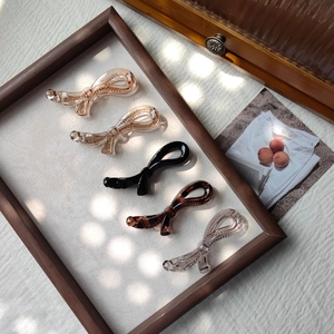 Lot de cinq pinces à cheveux en forme de nœud de couleurs variées sur fond de tissu neutre