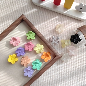 Flachbild von kleinen matten Pastell-Blumen-Haarclips in verschiedenen Farben auf weißem Stoff