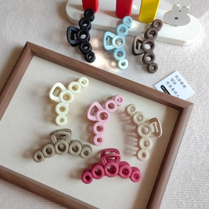 Detail showing seven colors of matte hollow circle hair claws on a textured background