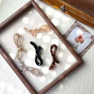 Détail de cinq barrettes banane élégantes en forme de nœud, ambre, noir et écaille de tortue