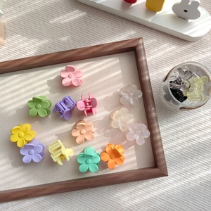 Makroaufnahme bunter matter Blumen-Haarklammern in einer Holzschale und einem Glas