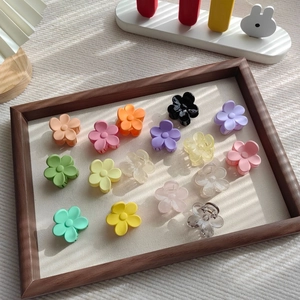 Matte und lichtdurchlässige Blumen-Haarklammern in Macaron-Farben auf Holztablett
