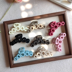 Detail view of colorful matte interlocking hollow circle hair claws in a wooden tray